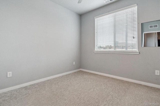 carpeted empty room with baseboards, visible vents, and a ceiling fan