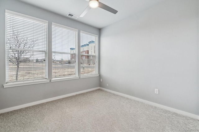 carpeted spare room with ceiling fan, visible vents, and baseboards