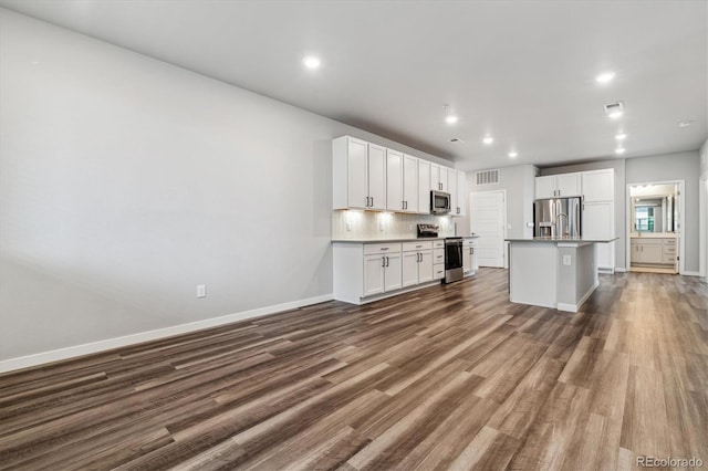 kitchen with dark wood-style floors, stainless steel appliances, tasteful backsplash, visible vents, and white cabinets