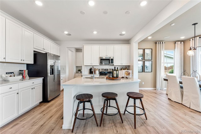 kitchen featuring stainless steel appliances, a sink, white cabinets, light countertops, and pendant lighting