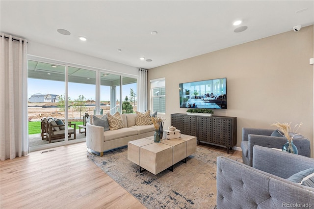 living area with light wood finished floors, visible vents, and recessed lighting