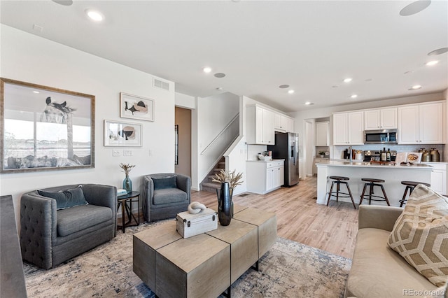 living room with light wood-style floors, stairs, visible vents, and recessed lighting