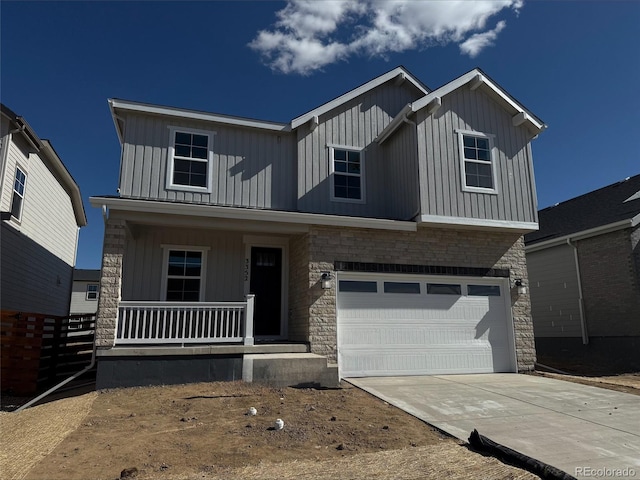 view of front of house featuring concrete driveway, stone siding, an attached garage, covered porch, and board and batten siding