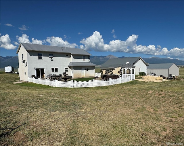 rear view of property with a lawn, a gazebo, and a mountain view