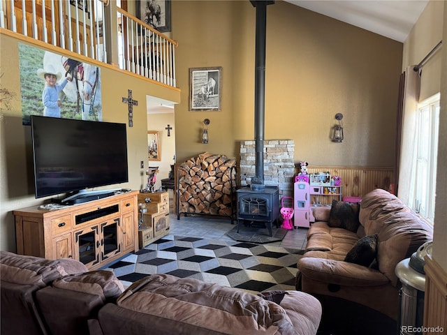 living room featuring vaulted ceiling, a wood stove, and wood walls