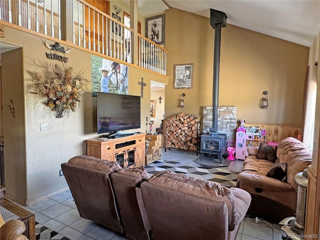 living room with light tile patterned floors, a wood stove, and a high ceiling