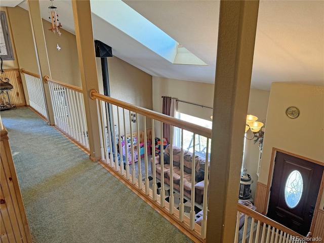 hallway with lofted ceiling with skylight and carpet flooring