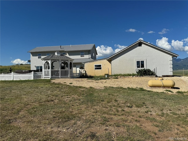 rear view of property featuring a gazebo and a lawn