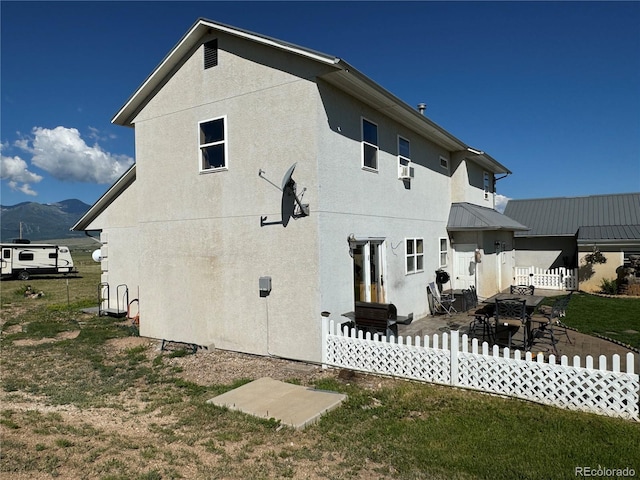 back of house featuring a mountain view, a patio area, and a yard