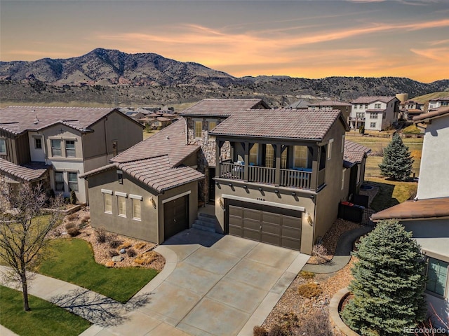 mediterranean / spanish-style home featuring a balcony, stucco siding, a mountain view, driveway, and a tiled roof