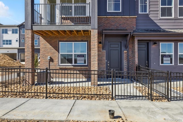 view of front of property featuring a fenced front yard, brick siding, and board and batten siding