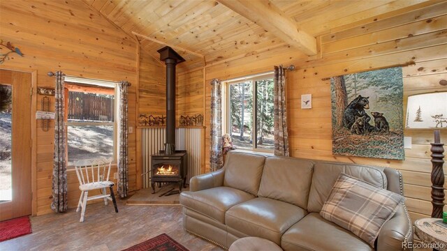 155 Squilchuck Trl, Woodland Park, CO 80863 - living area with wood walls, a wood stove, wood finished floors, wooden ceiling, and lofted ceiling with beams