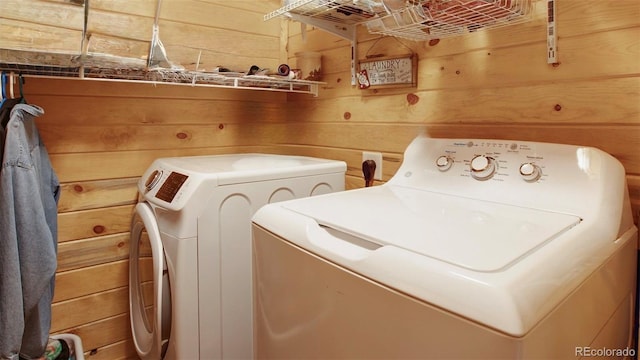laundry area with wooden walls, laundry area, and independent washer and dryer
