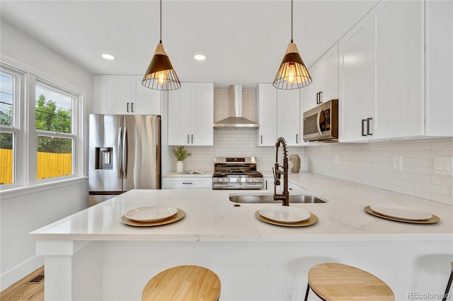 2701 Barnhart St, Thornton, CO 80229 - kitchen with wall chimney exhaust hood, appliances with stainless steel finishes, a peninsula, decorative light fixtures, and tasteful backsplash
