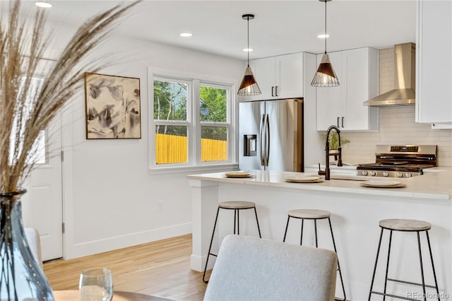 2701 Barnhart St, Thornton, CO 80229 - kitchen featuring wall chimney range hood, appliances with stainless steel finishes, a breakfast bar area, backsplash, and white cabinets