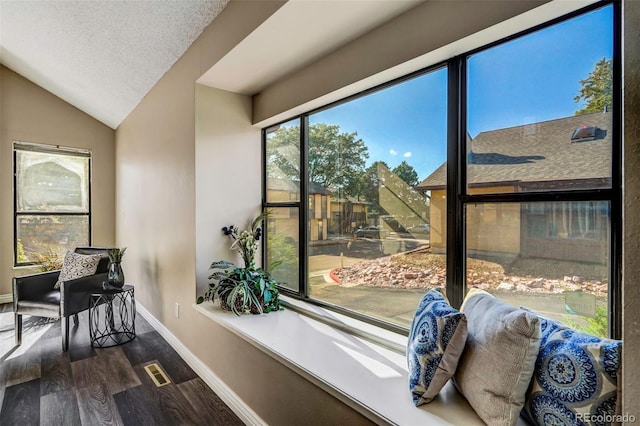 living area featuring vaulted ceiling, a textured ceiling, and hardwood / wood-style flooring