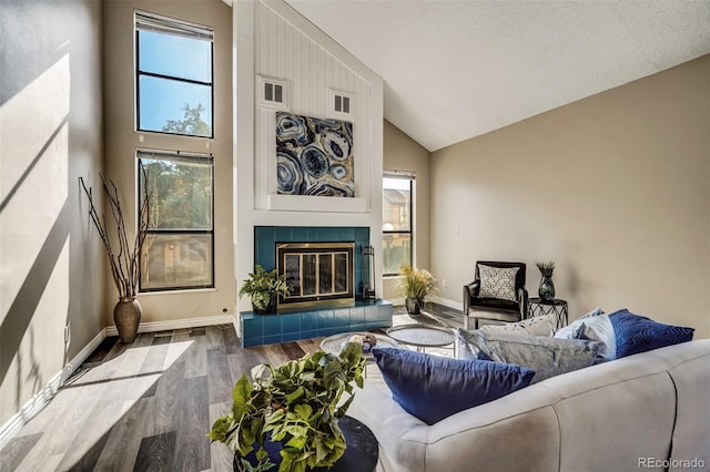 living room with light wood-type flooring, high vaulted ceiling, and a tile fireplace