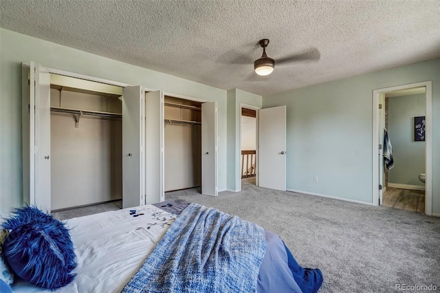 carpeted bedroom featuring a textured ceiling, two closets, ceiling fan, and ensuite bathroom