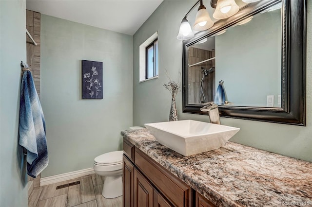 bathroom with a shower, hardwood / wood-style floors, toilet, and vanity