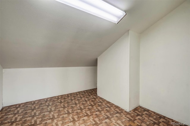 additional living space with dark parquet floors and vaulted ceiling