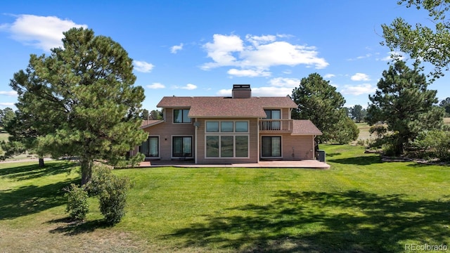 back of house with a balcony, a lawn, and a patio area