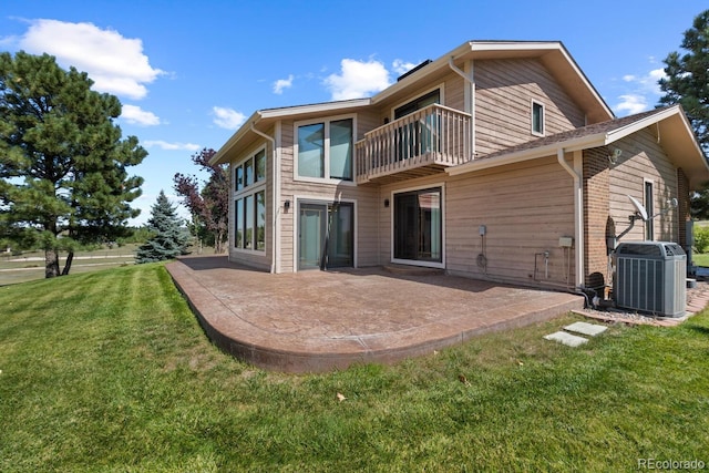 rear view of house with a patio, a balcony, a yard, and central AC