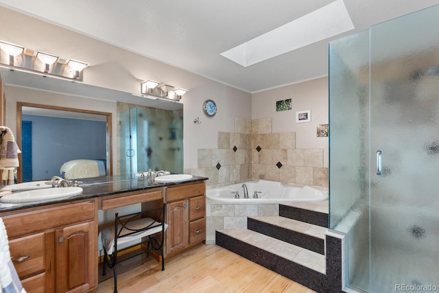 bathroom with shower with separate bathtub, wood-type flooring, vanity, and a skylight