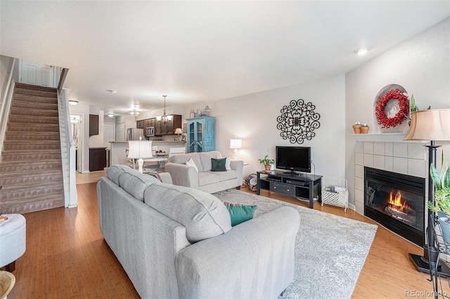 5252 W 68th Ave, Arvada, CO 80003 - living area featuring stairway, a tile fireplace, light wood-style floors, and a chandelier