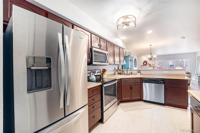 5252 W 68th Ave, Arvada, CO 80003 - kitchen featuring appliances with stainless steel finishes, a chandelier, a sink, a peninsula, and light countertops