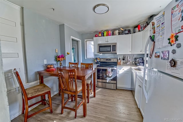 kitchen featuring white cabinets, light wood finished floors, stainless steel appliances, and light countertops