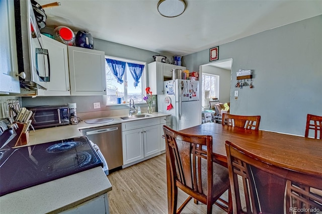 kitchen with white cabinets, light countertops, a sink, and stainless steel dishwasher