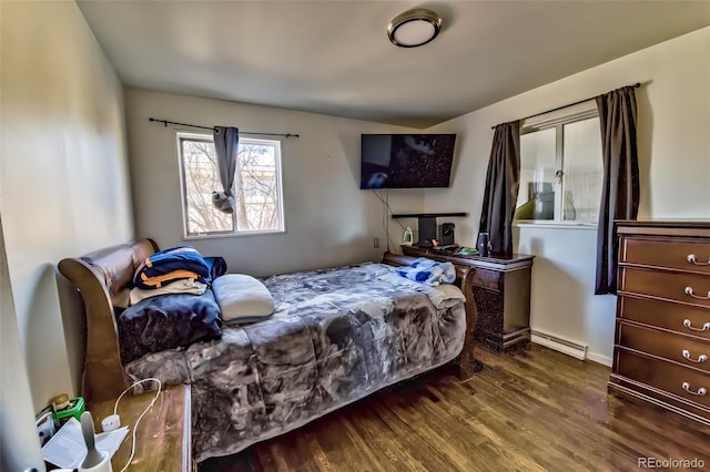 bedroom with baseboard heating and wood finished floors