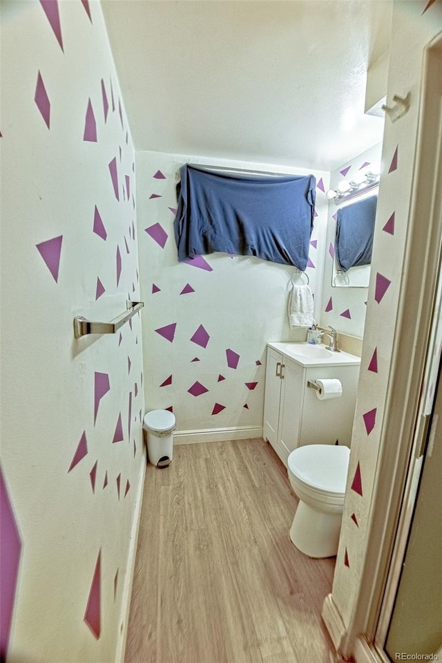 bathroom featuring toilet, wood finished floors, vanity, and baseboards