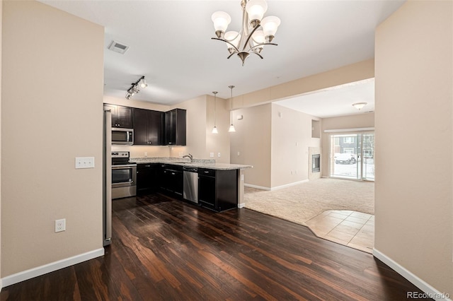 kitchen with stainless steel appliances, hanging light fixtures, dark hardwood / wood-style floors, kitchen peninsula, and a notable chandelier