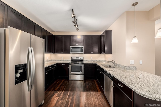 kitchen with decorative light fixtures, kitchen peninsula, sink, appliances with stainless steel finishes, and dark wood-type flooring