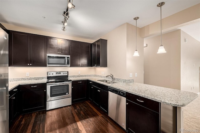 kitchen with kitchen peninsula, stainless steel appliances, light stone countertops, pendant lighting, and sink