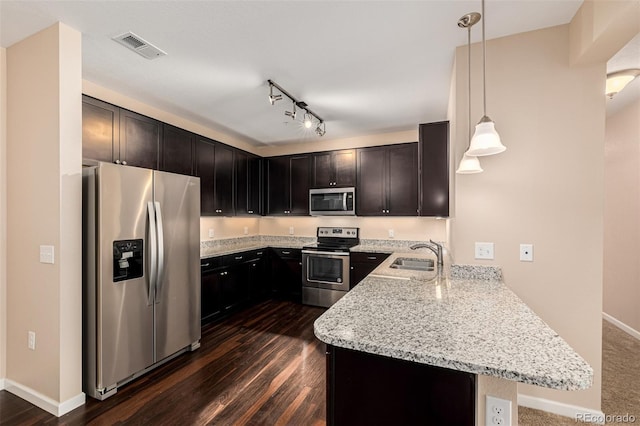 kitchen with light stone countertops, stainless steel appliances, sink, hanging light fixtures, and kitchen peninsula