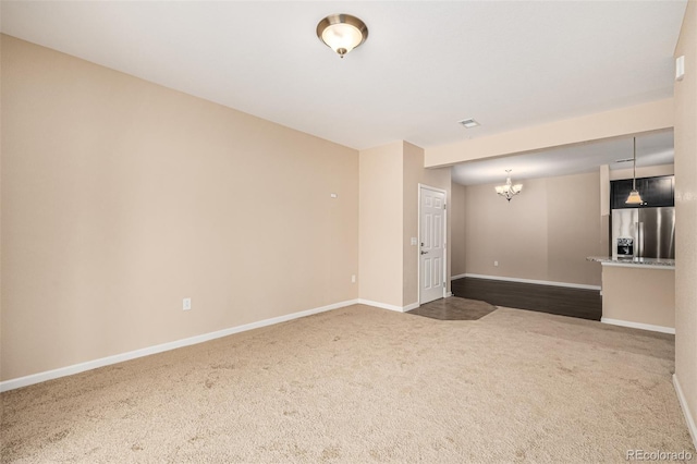 carpeted empty room with an inviting chandelier