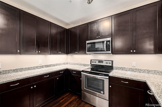 kitchen with dark wood-type flooring, stainless steel appliances, dark brown cabinets, and light stone countertops