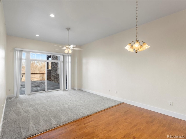 empty room with recessed lighting, baseboards, wood finished floors, and ceiling fan with notable chandelier