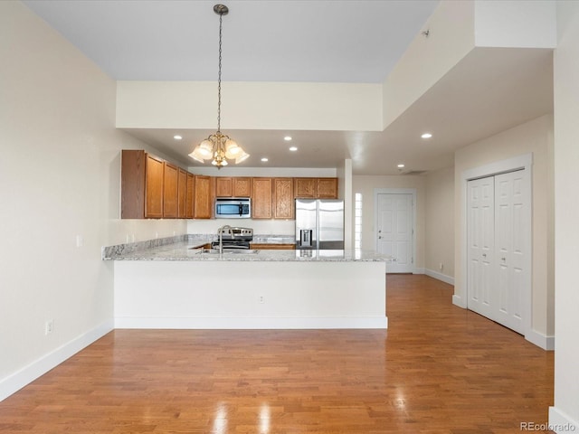 kitchen with recessed lighting, light wood-style floors, appliances with stainless steel finishes, a peninsula, and baseboards