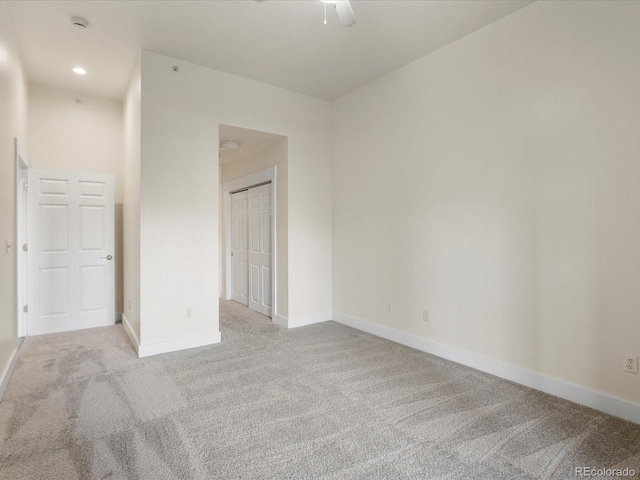 unfurnished bedroom with a closet, recessed lighting, light colored carpet, and baseboards