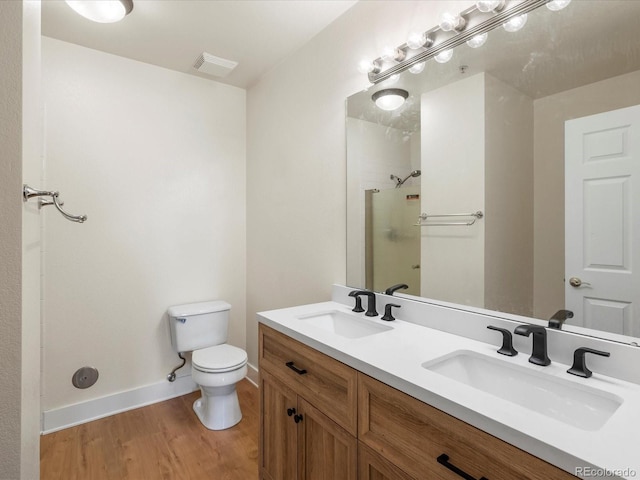 bathroom featuring visible vents, toilet, walk in shower, and a sink