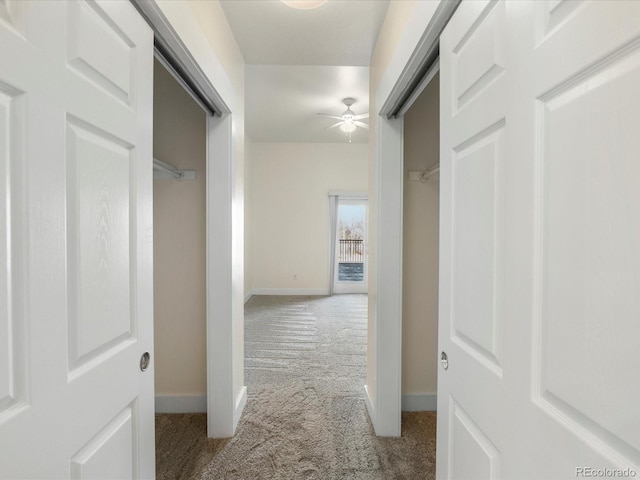 corridor featuring baseboards and carpet floors