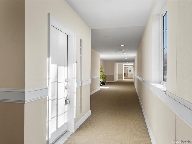 hallway featuring carpet flooring and baseboards