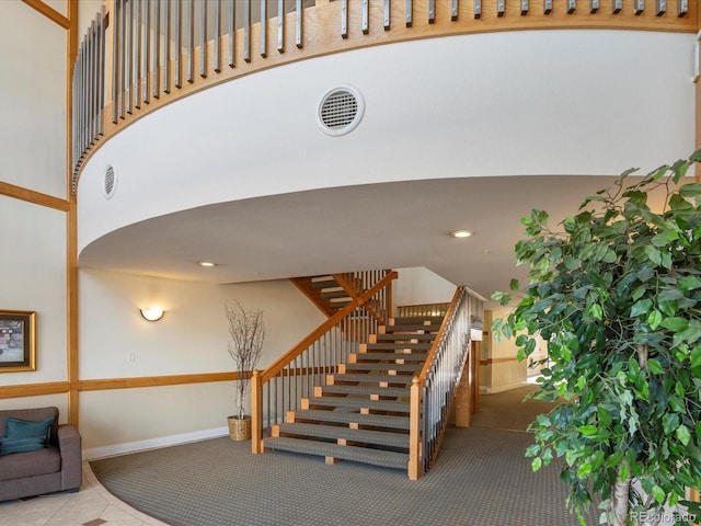 stairs featuring tile patterned flooring, recessed lighting, baseboards, and a towering ceiling