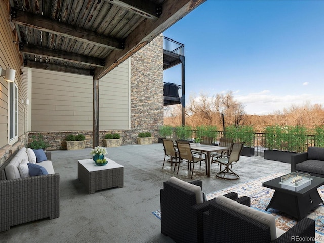 view of patio / terrace featuring a balcony and an outdoor living space with a fire pit