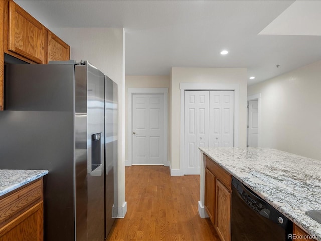 kitchen with brown cabinetry, black dishwasher, stainless steel fridge with ice dispenser, and light wood finished floors