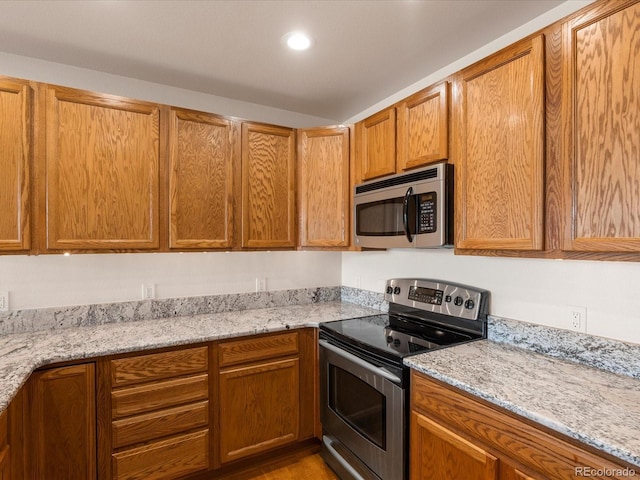 kitchen featuring light stone counters, brown cabinets, and appliances with stainless steel finishes