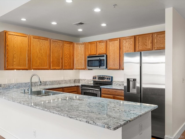 kitchen with light stone countertops, visible vents, a peninsula, a sink, and stainless steel appliances